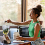 Young hispanic woman chopping ingredients for healthy smoothie in kitchen